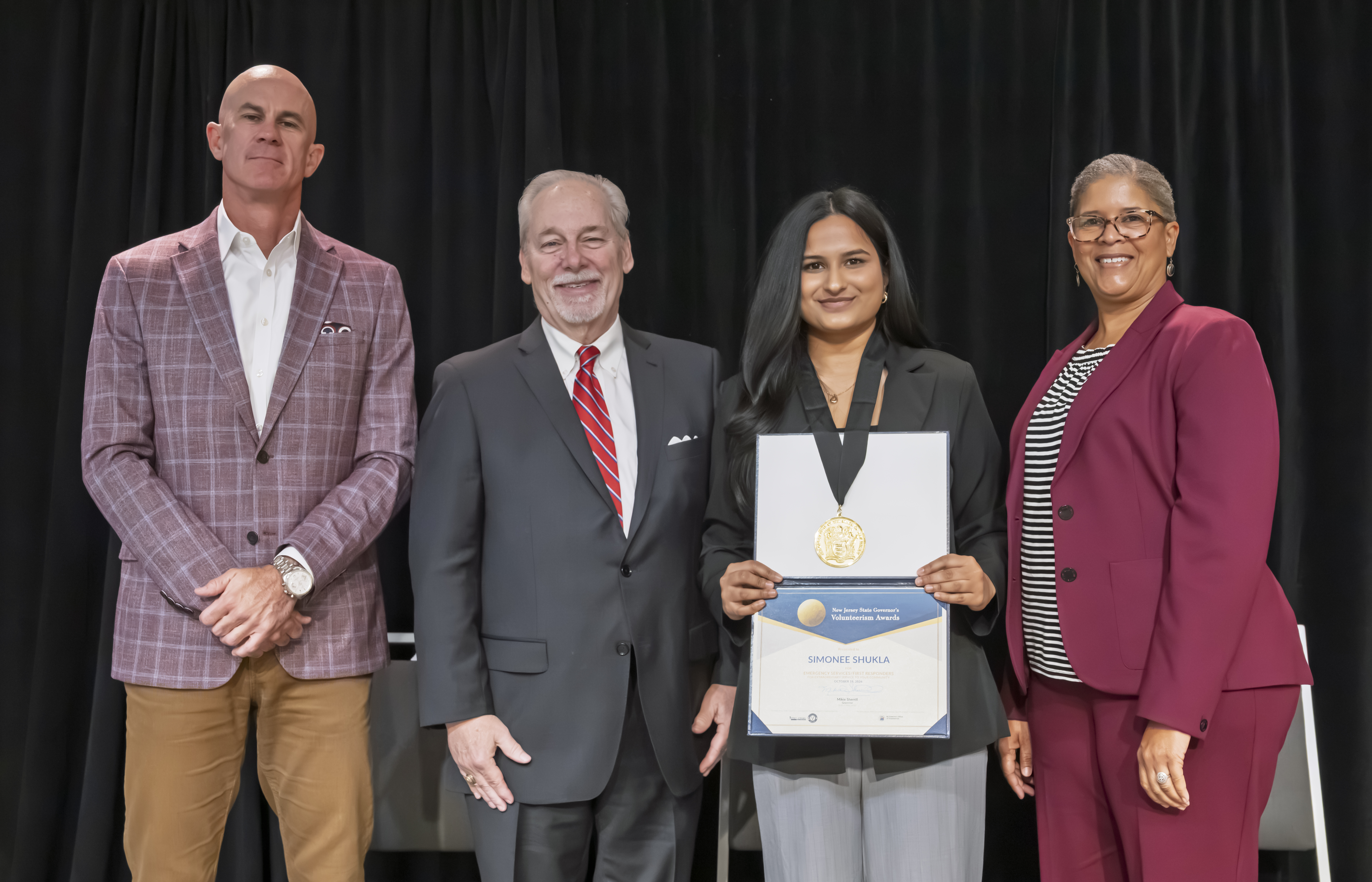 Simonee Shukla on stage with her medal and certificate during the awards ceremony